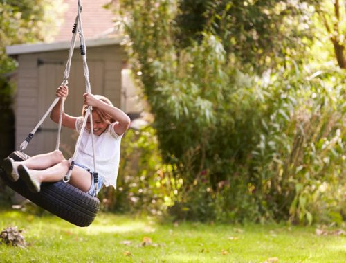 young-girl-playing-on-tire-swing-in-garden-PJQ4ZSN.jpg